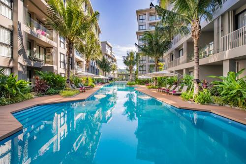 a swimming pool in the middle of a building with palm trees at Diamond Resort Phuket Official Account in Bang Tao Beach