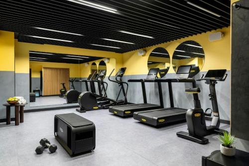 a gym with several tread machines and a tv at Le Parchamp, a Tribute Portfolio Hotel, Paris Boulogne in Boulogne-Billancourt