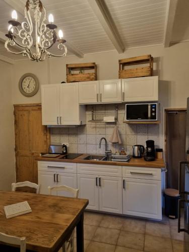 une cuisine avec des placards blancs, une table et un lustre dans l'établissement Gîte à la ferme Chez Chris, à Bollène