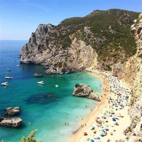 a group of people on a beach in the water at Apartamento Ferias- Praia da California, Sesimbra in Sesimbra