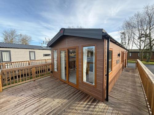 una terraza de madera con una casa pequeña. en Goldfinch Lodge at Brickyard Lakes, en Amotherby
