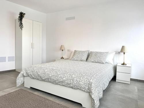 a white bedroom with a white bed and two lamps at Ocean View El Varadero in Punta Mujeres