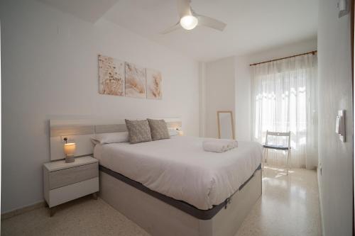 a white bedroom with a large bed and a window at SIBS Sanlúcar Océano-Ideal Familias-Parking y Wifi Gratis in Sanlúcar de Barrameda