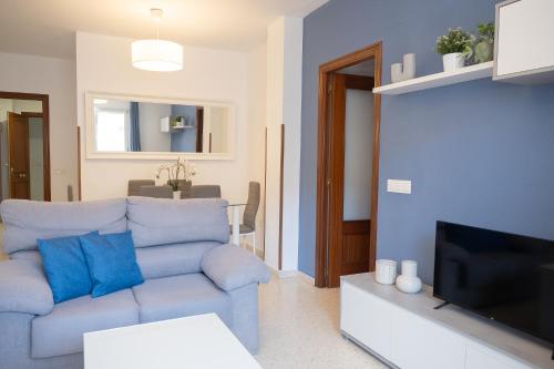 a living room with a blue couch and a tv at SIBS Sanlúcar Océano-Ideal Familias-Parking y Wifi Gratis in Sanlúcar de Barrameda