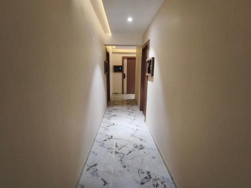 a hallway with a white marble floor and a corridorngthngthngthngthngthngth at Hotel Prime Suites Airoli in Navi Mumbai