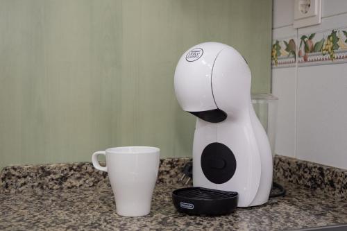 a white coffee maker sitting on a counter next to a cup at SIBS Sanlúcar Océano-Ideal Familias-Parking y Wifi Gratis in Sanlúcar de Barrameda