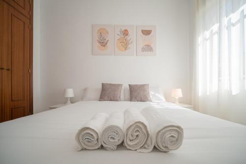 a white bed with three rolled towels on it at SIBS Sanlúcar Océano-Ideal Familias-Parking y Wifi Gratis in Sanlúcar de Barrameda