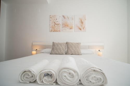 a white bed with three rolled towels on it at SIBS Sanlúcar Océano-Ideal Familias-Parking y Wifi Gratis in Sanlúcar de Barrameda