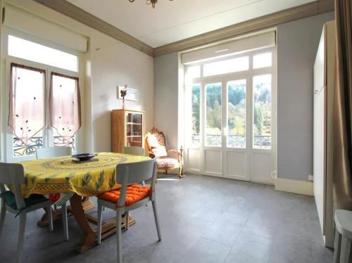 une salle à manger avec une table, des chaises et des fenêtres dans l'établissement Appartement Les Glycines, à Plombières-les-Bains