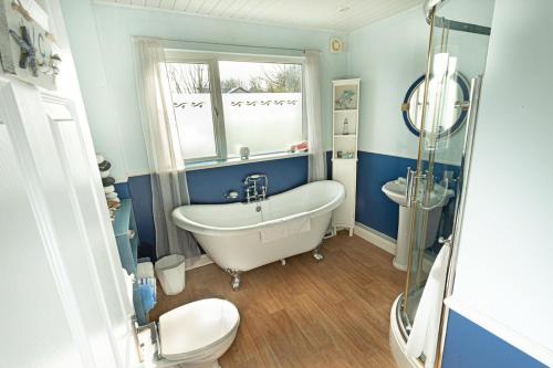a bathroom with a tub and a toilet and a sink at Smithy Cottage in Heysham