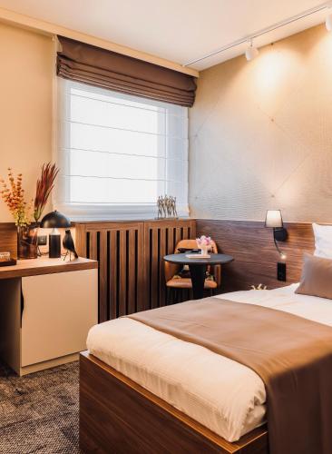 a bedroom with a bed and a desk and a window at Aqua Hotel Termál in Mosonmagyaróvár