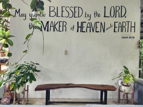 a wooden bench against a wall with a sign on it at Sotera and Paz Forestville in Silang