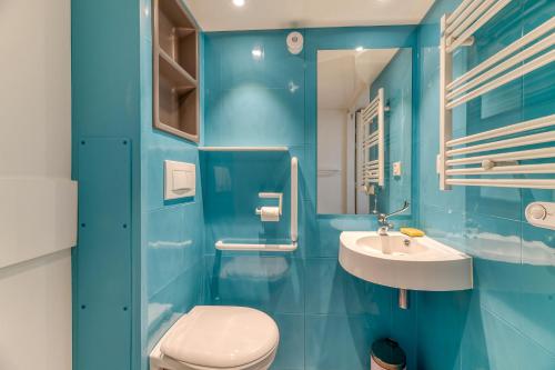 a blue bathroom with a toilet and a sink at Logis Les Forges in Arvillard