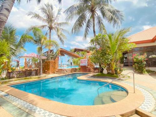 a pool at the resort with palm trees at Marick Beach Resort in Carmen