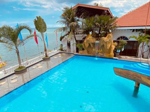 a pool in front of a house with the ocean in the background at Marick Beach Resort in Carmen