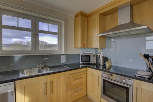 a kitchen with wooden cabinets and a sink at No17 The Links Apartment, Brora in Brora