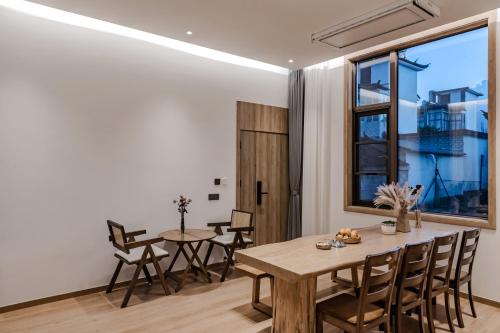 a dining room with a wooden table and chairs at 墨弦苑智能轻奢民宿 喜洲镇海舌公园店 in Dali