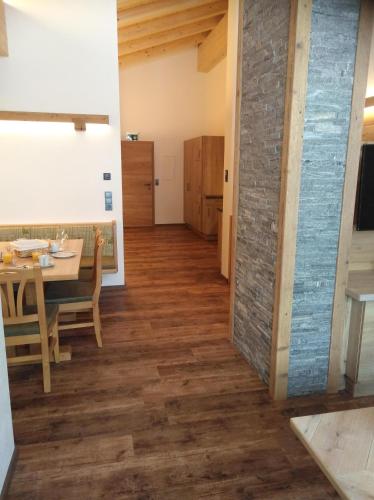 a kitchen and dining room with a table and a room with a brick wall at Ferienwohnungen Recherhof in Hochfilzen