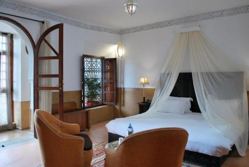 una camera da letto con un letto a baldacchino e due sedie di Riad Charaï a Marrakech