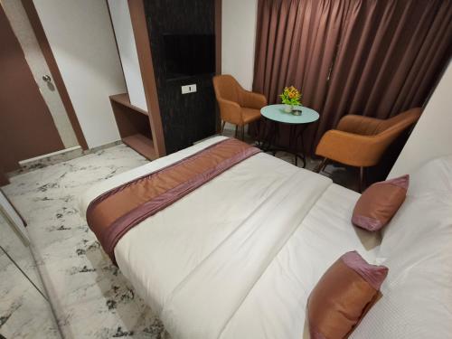 a hotel room with a bed and a table and chairs at Hotel Prime Suites Airoli in Navi Mumbai