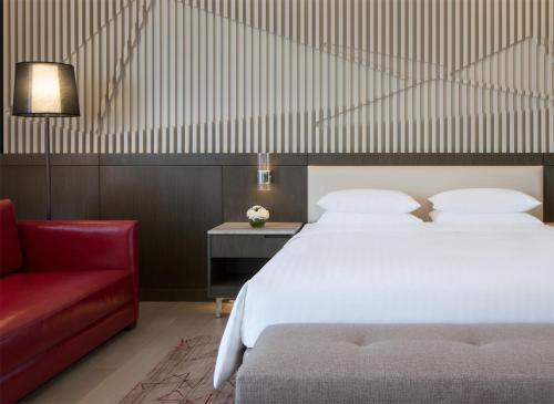 a bedroom with a bed and a red couch at Courtyard by Marriott Tianjin Hongqiao in Tianjin