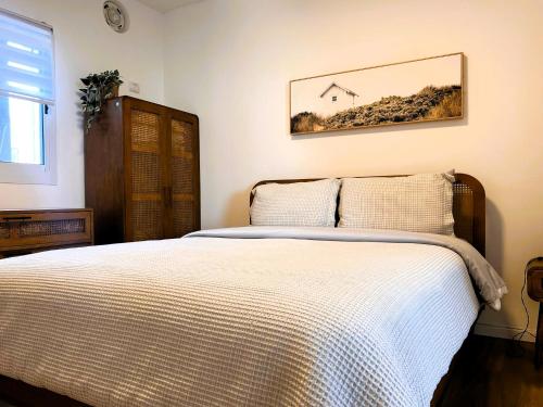 a bedroom with a bed and a picture of a house at הדירה- C Lake, סי כנרת in Migdal