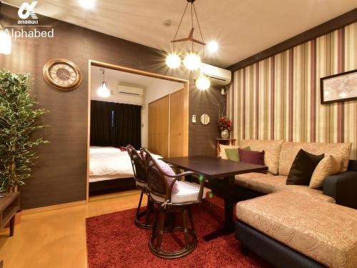 a living room with a couch and a table and a bed at Alphabed松山城西 in Matsuyama