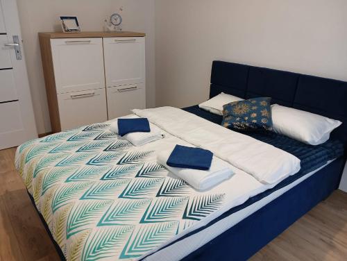 a bed with blue and white sheets and pillows on it at Apartament Fale Bałtyku in Kołobrzeg