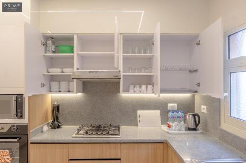 a kitchen with white cabinets and a counter top at Prime Residence Zayed Heights in Sheikh Zayed