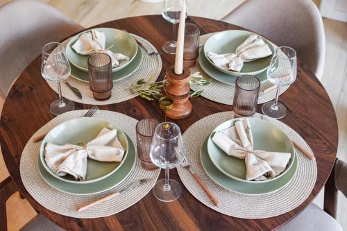 a wooden table with plates and wine glasses on it at Charming Villa Harmonia with Heated pool and Indoor Jacuzzi surrounded by nature in Pićan