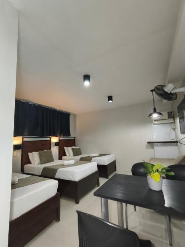 a room with three beds and a table and a dining room at Delle Suites in General Santos