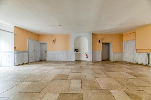 an empty room with a tile floor and yellow walls at Logis Belledonne in Arvillard