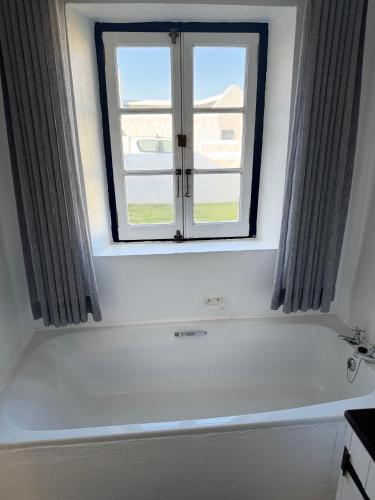 a bathroom with a bath tub and a window at Shoreline Cottage in Struisbaai