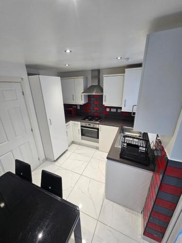 a kitchen with white cabinets and a black counter top at Very cosy 3 bedroom house close to city in Longford