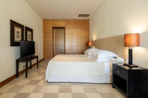 ein Schlafzimmer mit einem weißen Bett und einem Flachbildfernseher in der Unterkunft Plaza Resort in Anavyssos