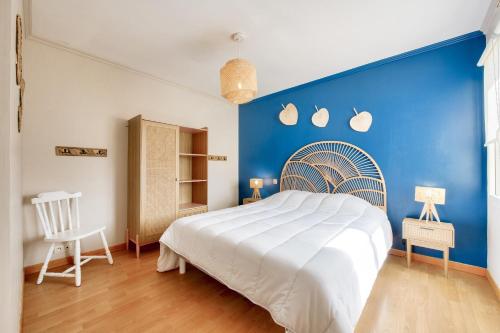 a bedroom with a large bed with a blue wall at Maison pour 6 avec jardin à 500 m de la plage in Lilia