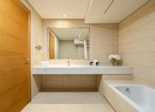a bathroom with a sink and a tub and a mirror at Plaza Resort in Anavyssos