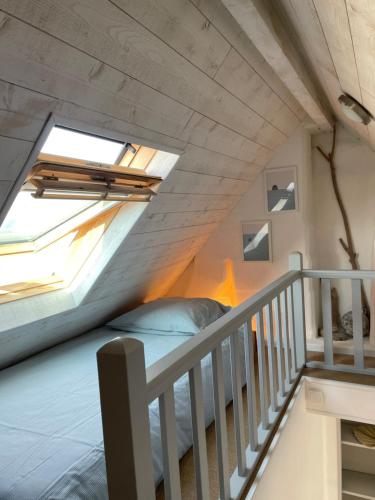 un lit dans une petite pièce avec une fenêtre dans l'établissement L'Escapade, à Fort-Mahon-Plage