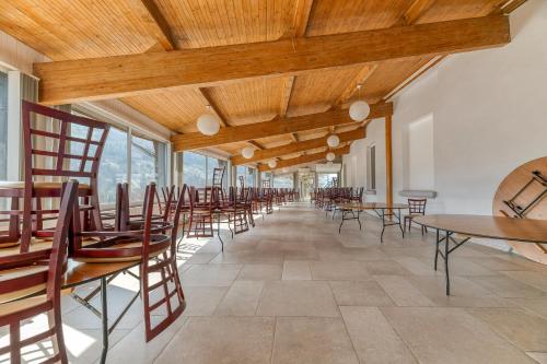 a row of tables and chairs in a room with windows at Logis Belledonne in Arvillard