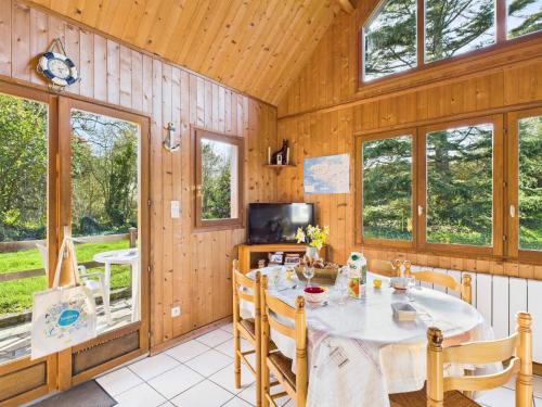 une salle à manger avec une table, des chaises et des fenêtres dans l'établissement Chalet 2 adultes 2 enfants - jardin et terrasse, à Plurien