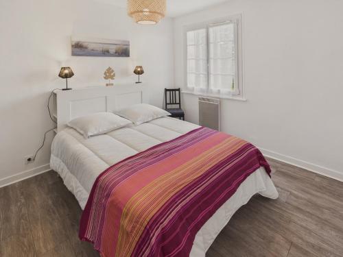 une chambre avec un grand lit avec une couverture colorée dans l'établissement Appartement pour 4 à 5 minutes de la plage, à Loctudy