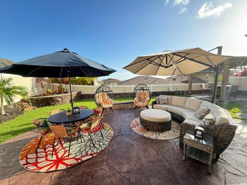 a patio with a table and chairs and an umbrella at New 4 Bedroom Home with Ocean and Gorgeous Mountain Views in the gated community of Mauna Olu in Waianae