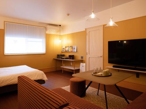 a room with a bed and a television and a table at デザイナーズホテル アリス -Adult only- in Sasebo