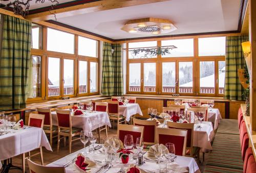 un restaurante con mesas y sillas blancas y ventanas en Monarchia Park en Lachtal
