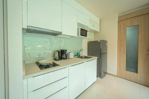 a kitchen with white cabinets and a stainless steel refrigerator at A New Experience of Private Vacation and Work in Patong in Patong Beach