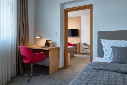 a bedroom with a bed and a desk with a laptop at Hotel Osvit in Mladá Boleslav