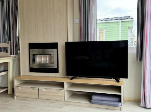 a flat screen tv sitting on a stand in a living room at PG177 Golden Palm Resort 8 Berth Caravan With Decking in Chapel Saint Leonards