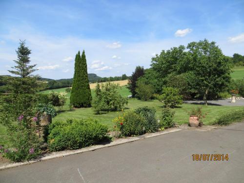 a garden with trees and flowers and a road at Ferienwohnungen Grafenfelder Hof in Gerolstein