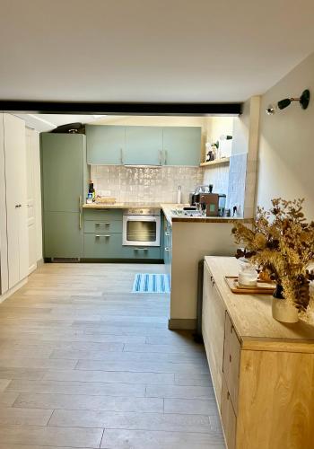 une cuisine avec des placards verts et un comptoir dans l'établissement La Belle Villervillaise, à Villerville