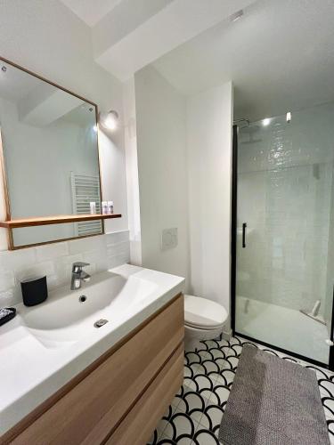 une salle de bain avec un lavabo, des toilettes et un miroir dans l'établissement La Belle Villervillaise, à Villerville